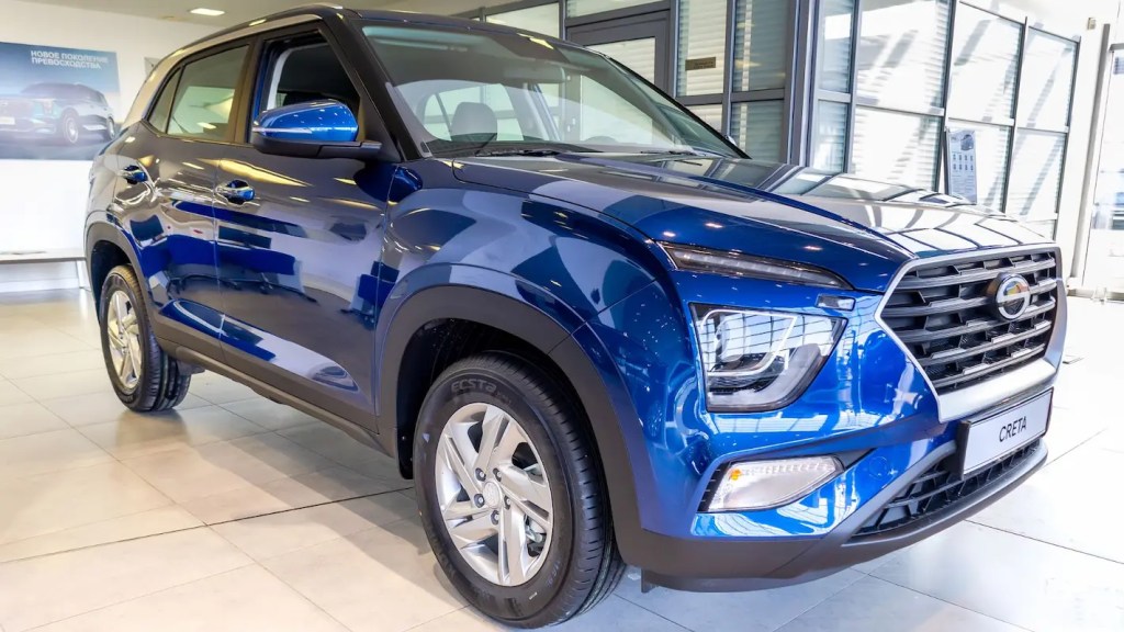 Hyundai Creta azul escuro exposto em showroom com foco no conjunto óptico dianteiro.
