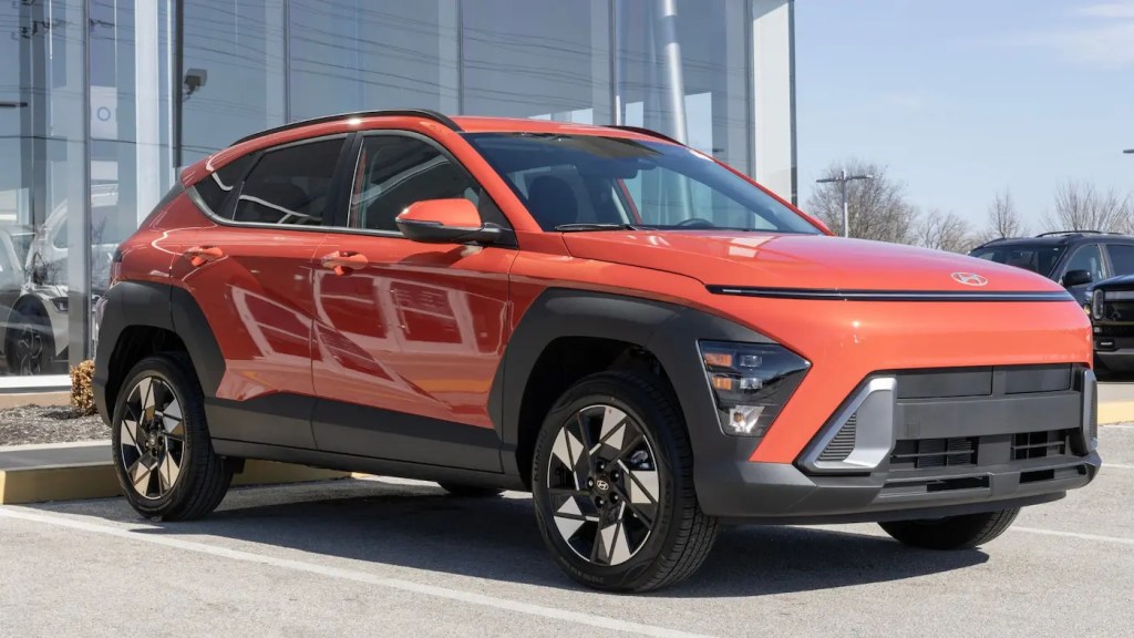 Hyundai Kona laranja de nova geração estacionado em frente a uma concessionária.