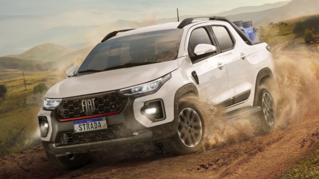 Picape Fiat Strada de cabine dupla e cor branca, um dos carros da fiat mais vendidos, em ação off-road em terreno de terra, levantando poeira.