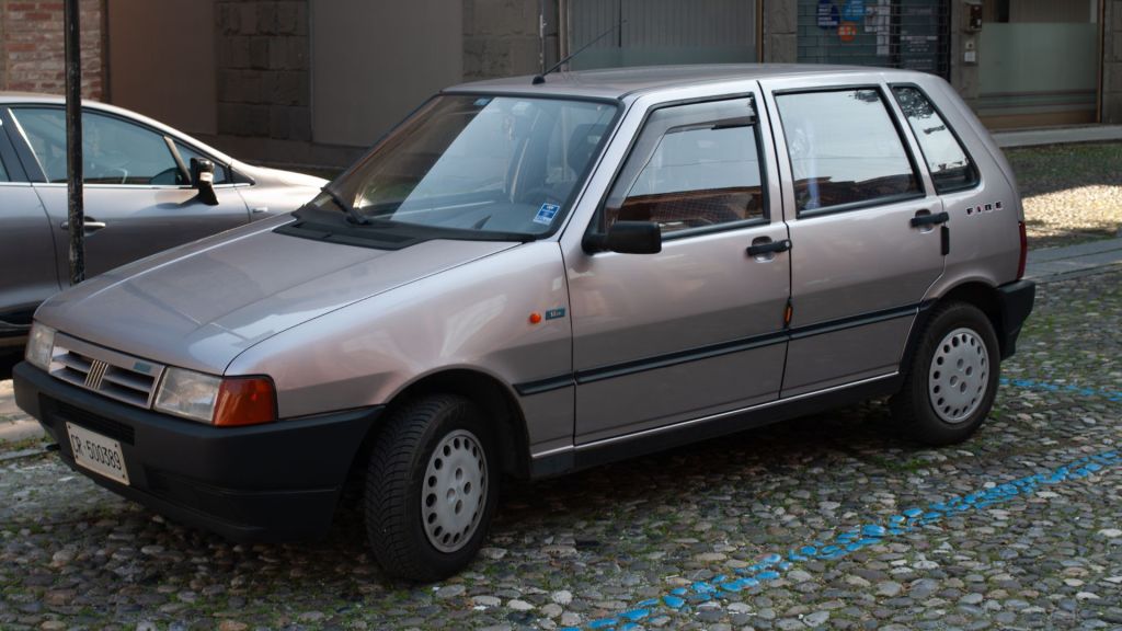 Imagem em movimento de um Fiat Uno (segunda geração) de cor cinza, um modelo icônico e econômico na história dos carros da fiat.
