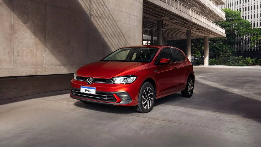 Carro hatch vermelho do modelo Polo estacionado em uma vaga de fundo cinza, uma boa opção de carros até 100 mil.
