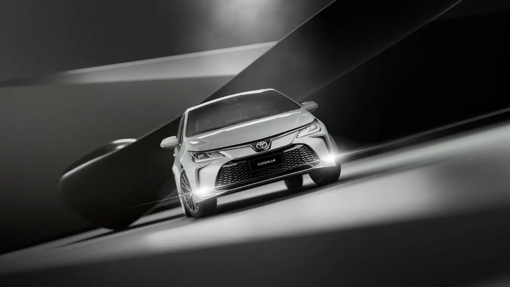 Sedã Toyota Corolla em movimento com faróis acesos, representando um dos carros até 150 mil mais buscados, com foco em conforto, tecnologia e eficiência no dia a dia.
