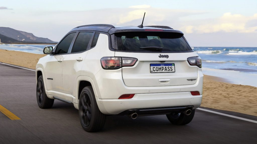 Carro de jeep de costas andando em uma rodovia proxima a praia