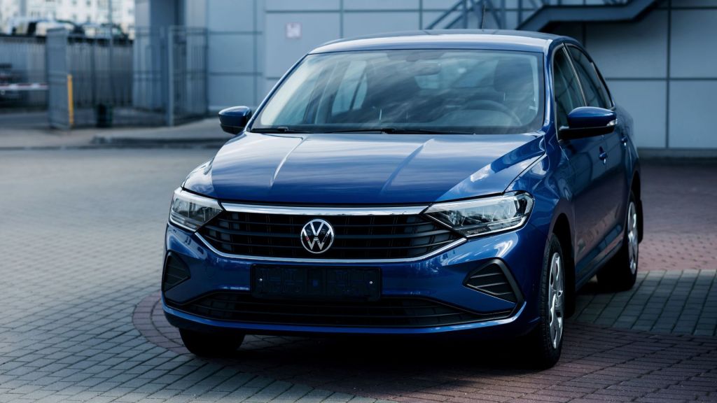 Melhor carro custo-benefício: Volkswagen sedã azul visto de frente em rua pavimentada.