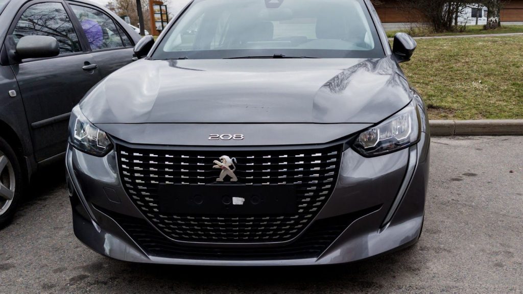 Detalhe frontal do Peugeot 208 cinza escuro. Modelo que se destaca entre os carros com teto solar até 50 mil.