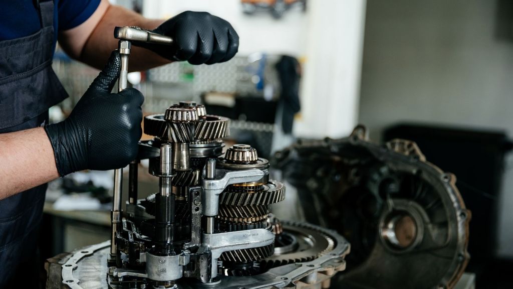 Mecânico especializado realizando o reparo e ajuste das engrenagens internas de um câmbio automático.