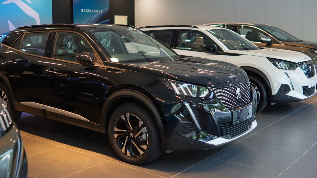 Fileira de carros Peugeot 2008 em concessionária mostrando diferentes cores e versões da nova geração 2025.