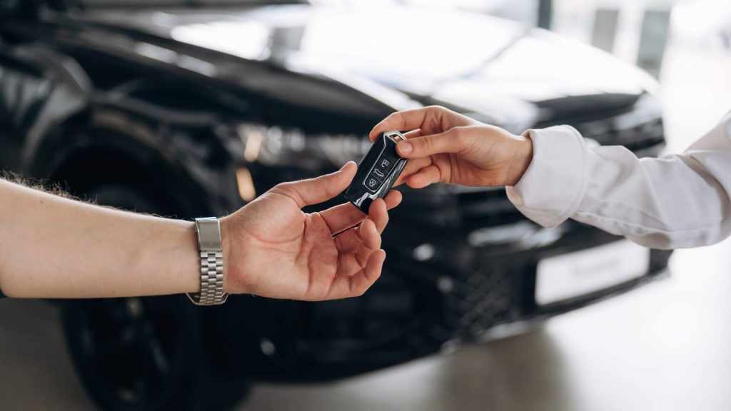 Pessoa entregando a chave de um veículo para outra, representando o momento ideal de quando trocar de carro com segurança e planejamento.