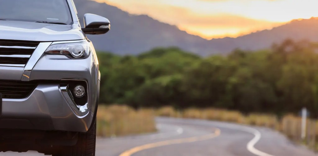 Imagem de um SUV moderno em estrada sinuosa ao entardecer ilustra os melhores SUVs para viagens, conforto, desempenho, segurança, tecnologia e versatilidade no dia dia.